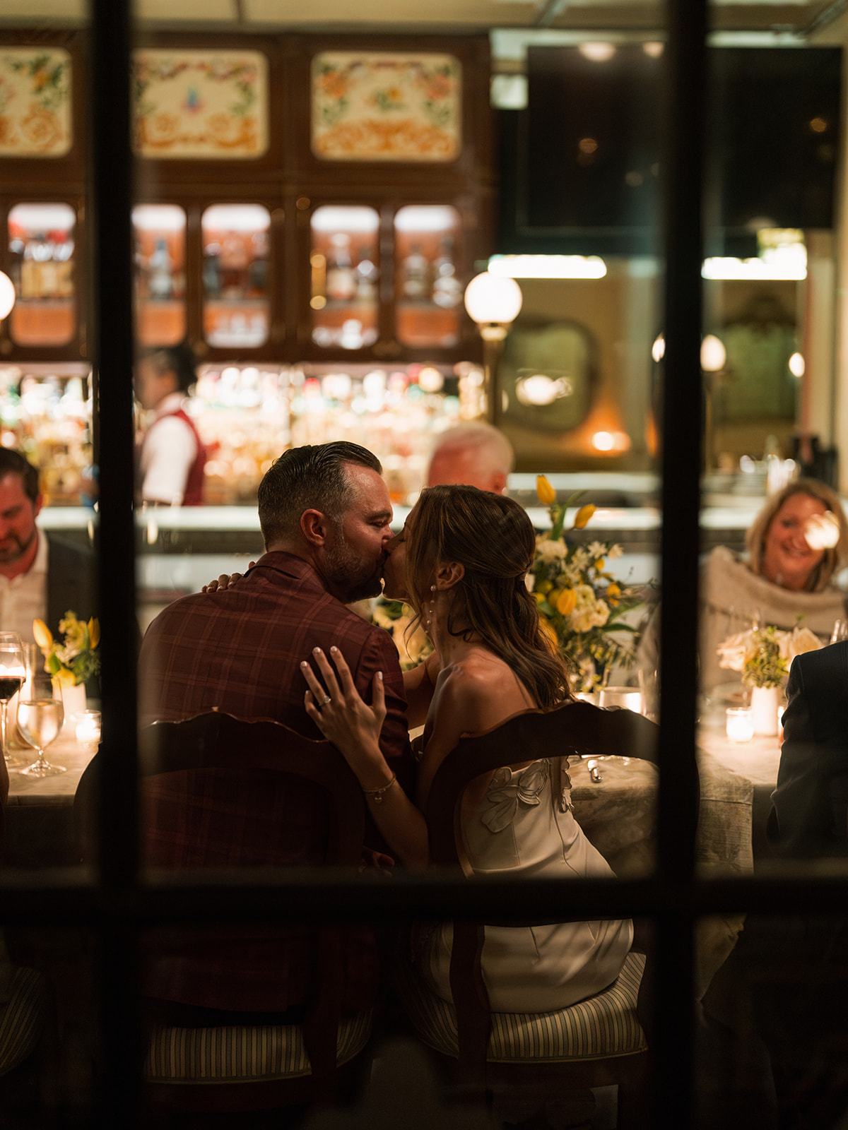 Couple sharing a kiss during a candlelit Carbone rehearsal dinner in Dallas at an intimate wedding rehearsal dinner celebration.